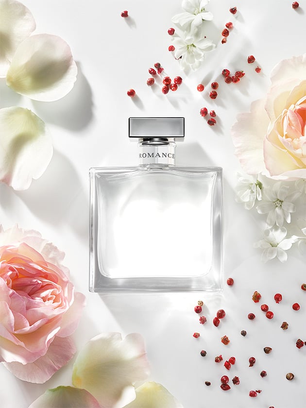 Bottle of Romance fragrance surrounded by flowers & pink peppercorns