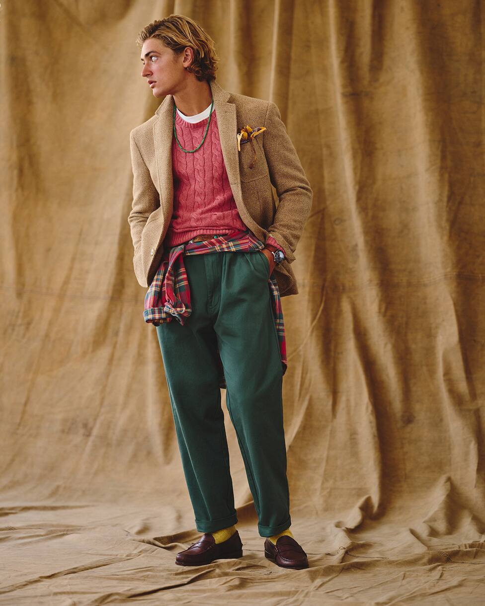 Hombre con un jersey rojo, un blazer beis, pantalones vaqueros y mocasines.